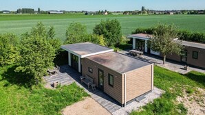 A modern, single-story building with a flat roof, large windows, and a patio area with outdoor furniture.