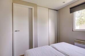 A bedroom with a bed, a white door, and a window with blinds.