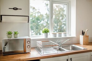 A kitchen with a microwave, a sink, wooden countertops, and a window with plants. - Central Cactus Luxurious Home | Free Parking 10PPL (Sheffield)