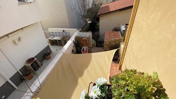 A narrow courtyard with a stone wall, a small table, and potted plants.