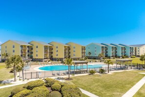 Ein Hotel mit mehrstöckigen Gebäuden, einem zentral gelegenen Schwimmbad und gepflegten Rasenflächen.