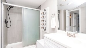 A modern bathroom with a shower, a large mirror, and a white vanity. - Beach Life - Updated 1 BR Condo - Sleeps 4 (Surf City)
