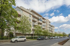 Ein mehrstöckiges Wohngebäude mit Balkonen, einem Parkplatz und blauem Himmel.