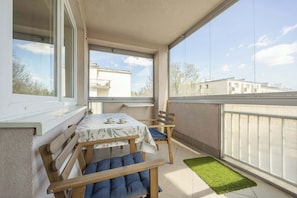 Ein Balkon mit Tisch und Stühlen, einem grünen Teppich und Blick auf Gebäude.