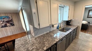 A modern kitchen with granite countertops, stainless steel appliances, and a view to the living area. - Backyard Escape + Hot Tub - Minutes to Red Rocks & Denver-Large Basement Hangout (Arvada)