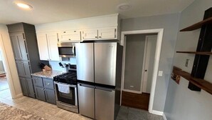 A modern kitchen with stainless steel appliances, grey cabinets, and a granite countertop. - Backyard Escape + Hot Tub - Minutes to Red Rocks & Denver-Large Basement Hangout (Arvada)