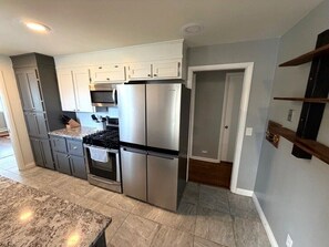 A modern kitchen with stainless steel appliances, grey cabinets, and a granite countertop. - Backyard Escape + Hot Tub - Minutes to Red Rocks & Denver-Large Basement Hangout (Arvada)
