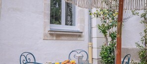 Ein Gebäude mit Außenansicht, einem Fenster, einem Tisch mit Stühlen und einer Pflanze.