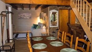 A wooden dining table with chairs, a staircase, a sofa, and a lamp. - Le P'tit Chalet, at 1000m altitude (Campan)