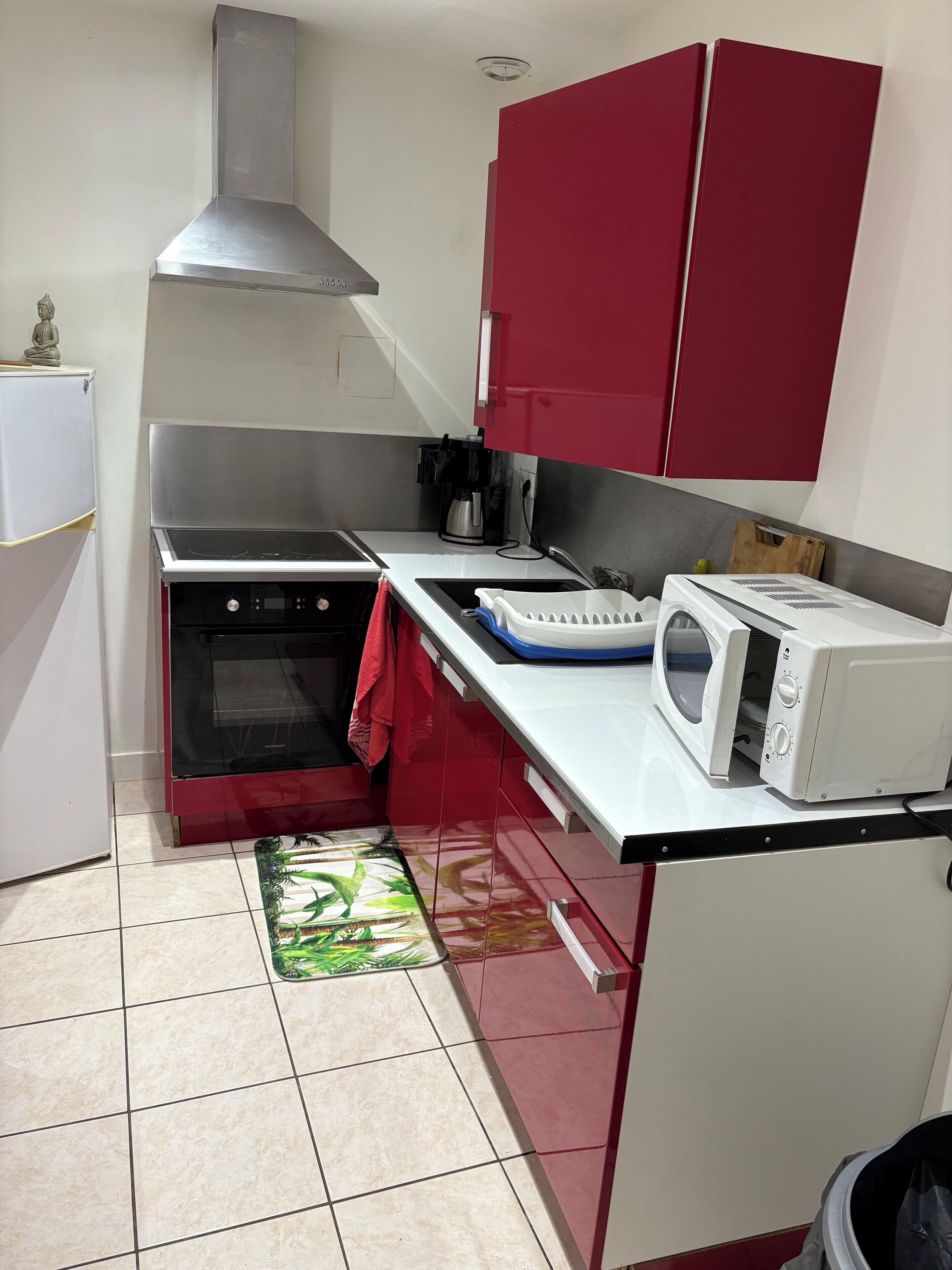 A compact kitchen with a stove, microwave, and red cabinets.