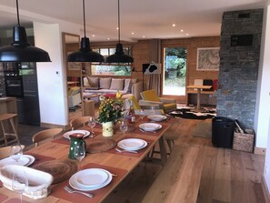 Ein Essbereich mit einem Holztisch, gedeckt für vier Personen, einer Blumenvase und einer Steinwand.