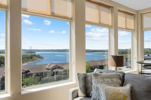 Ein Zimmer mit großen Fenstern mit Seeblick, einer Couch mit Kissen und einer Lampe.