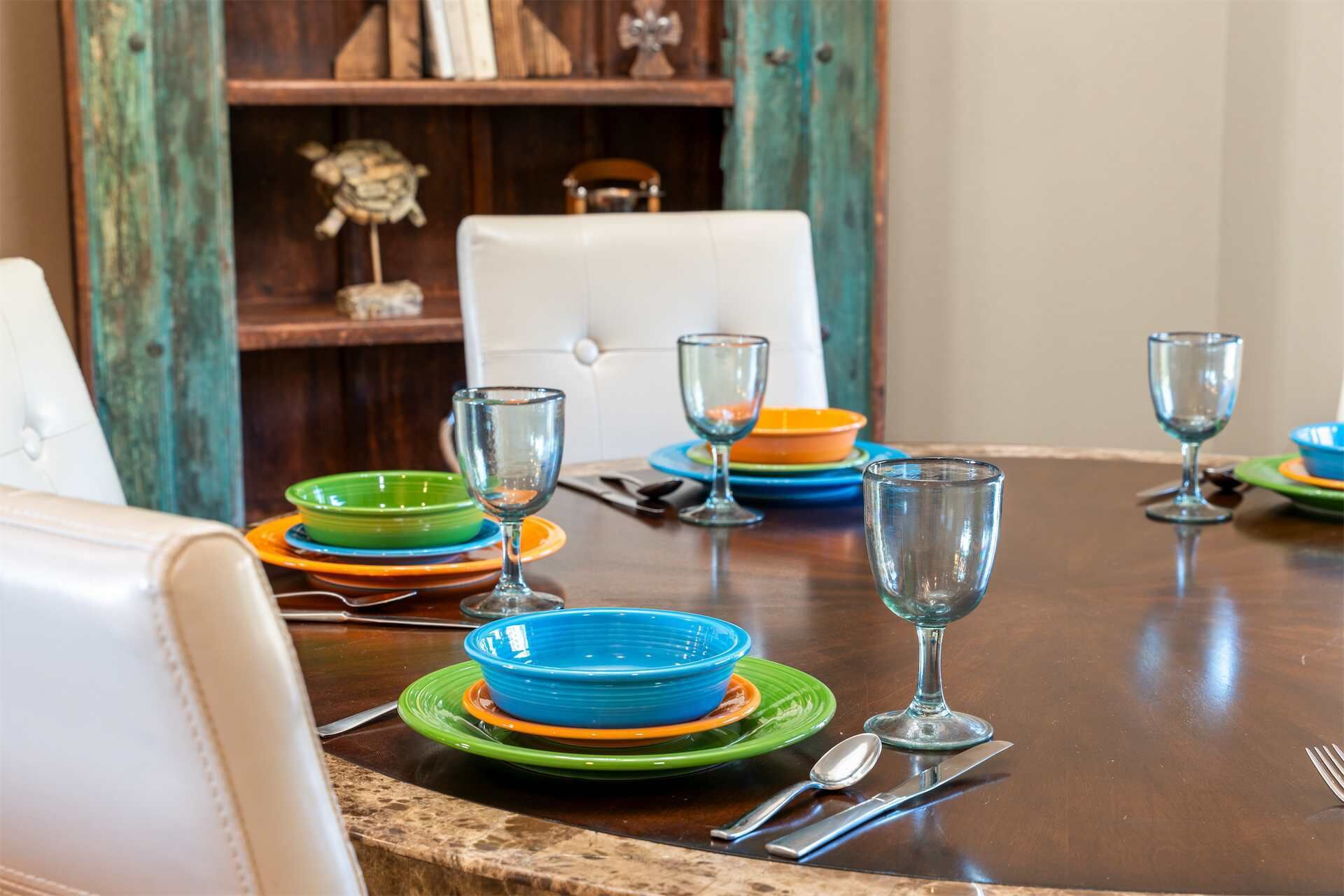 A dining table set with multiple plates and glasses, a chair, and a decorative item on a wooden table.