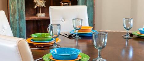 Una mesa de comedor dispuesta con varios platos y vasos, una silla y un adorno sobre una mesa de madera.