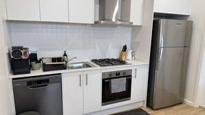 Une cuisine moderne avec des armoires blanches, un réfrigérateur en acier inoxydable, un four encastré et un lave-vaisselle.