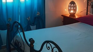 Una camera da letto con un letto, tende, un comodino con una lampada e una finestra.