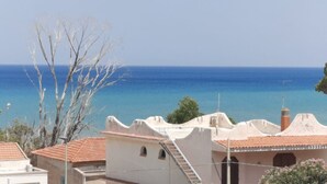 Un edificio sul lungomare con vista sul mare, una scala e un albero in primo piano.