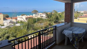 Un balcone con vista sul mare, un tavolo con una tovaglia fantasia e un corrimano.