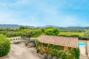 Una villa con techo de tejas, piscina y vistas al campo.