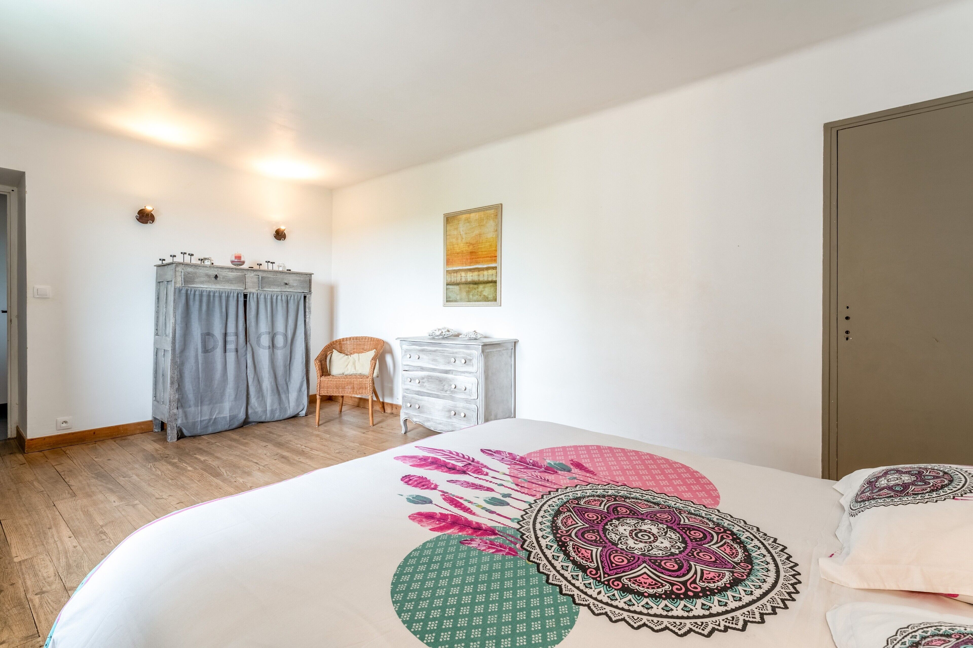 Une chambre à coucher avec un lit, une armoire, une chaise et une commode.
