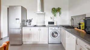 Een moderne keuken met roestvrijstalen apparatuur, een wasmachine en een magnetron.