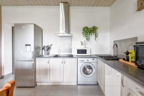 Una cocina moderna con electrodomésticos de acero inoxidable, lavadora y microondas.