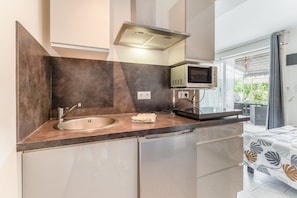 A compact kitchen with a sink, microwave, and a small TV. - Gite Lavande – La Bastide St Jacques (Vinsobres)