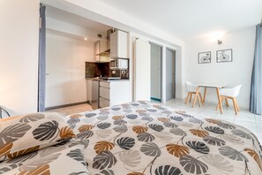 Un dormitorio moderno con una cama grande, una kitchenette, un comedor y un baño.