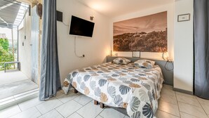 Ein Schlafzimmer mit einem Bett, einem Fernseher, einem großen Fenster und Blick auf eine Landschaft.