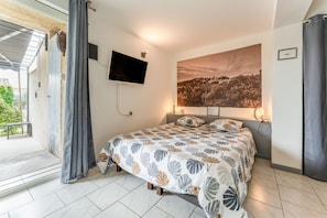 A bedroom with a bed, a TV, a large window, and a view of a landscape. - Gite Lavande – La Bastide St Jacques (Vinsobres)