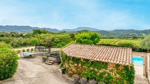 Eine Villa mit Ziegeldach, Swimmingpool und Blick ins Grüne.