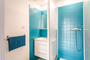 Un baño con azulejos azules, un lavamanos blanco, un espejo y un perchero para toallas.