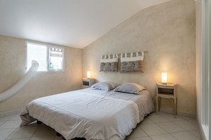 A bedroom with a bed, two bedside tables with lamps, a window with a curtain, and a wall-mounted light fixture. - Gite les vignes – La Bastide St Jacques: Provençal Retreat Amidst Organic Vineyards (Vinsobres)