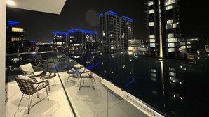 A rooftop pool area with lounge chairs and a view of illuminated buildings at night. - Maison Privee - Modern Family Retreat w/ Dubai Skyline Views (Dubai)