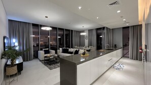 A modern kitchen with a central island, dining area with a sofa, and a visible kitchen counter. - Maison Privee - Modern Family Retreat w/ Dubai Skyline Views (Dubai)