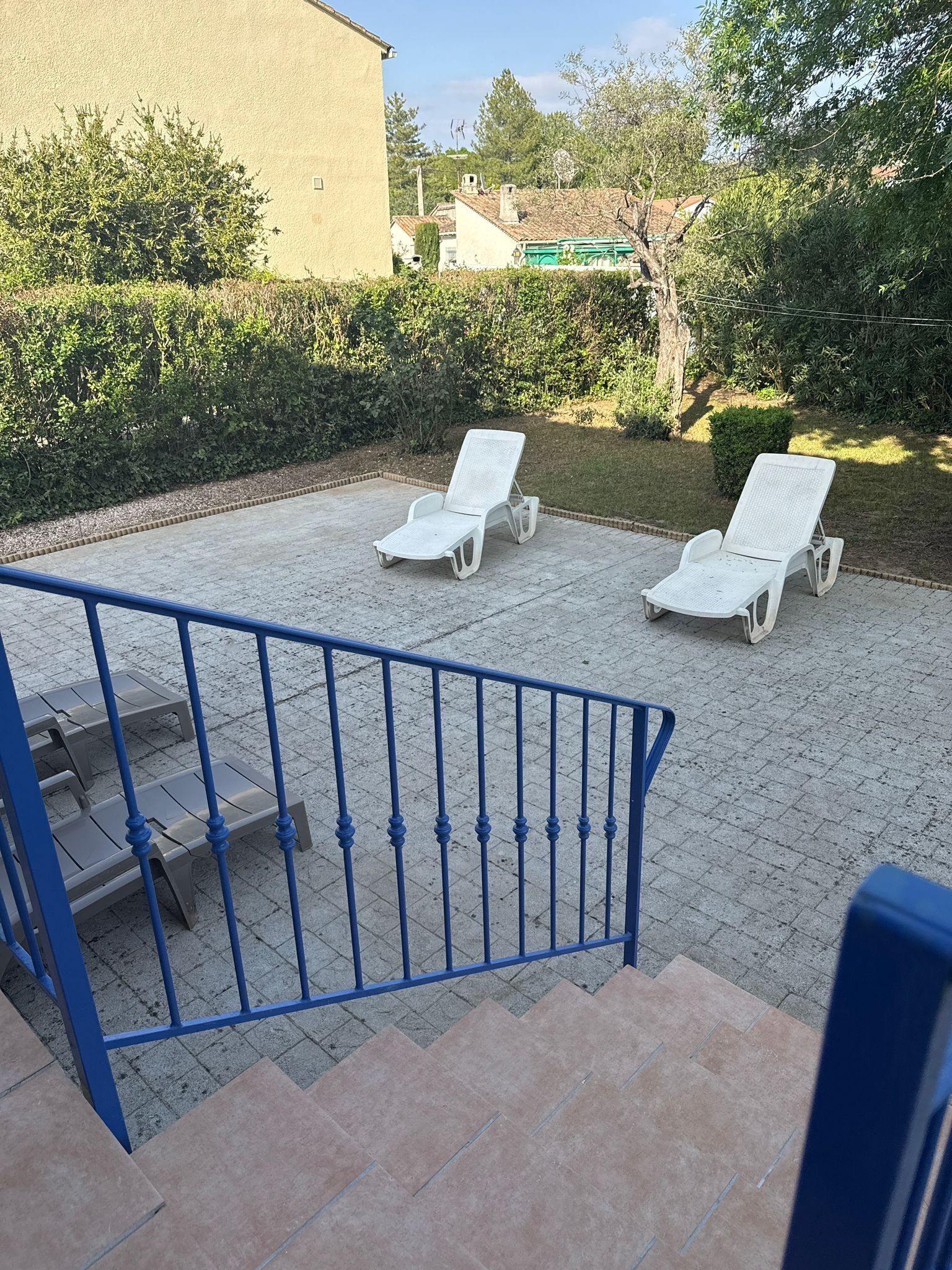 A courtyard with two white lounge chairs, a blue staircase, and a building in the background.