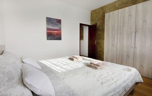 Ein Schlafzimmer mit Bett, Kissen, einem Gemälde und einem Kleiderschrank.