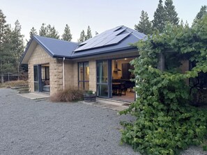 A modern house with a stone facade, large windows, and a solar panel roof. - Fantail Retreat - Twizel Escape (Twizel)