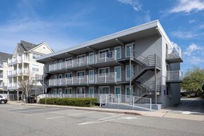 A multi-story hotel with balconies, a parking lot, and a clear sky. - Charming 1 Bedroom, Two Bath Condo in Desirable North Ocean City (Ocean City)