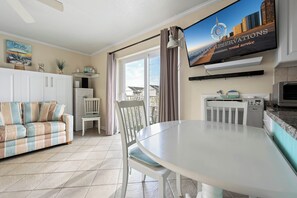 A modern living room with a sofa, dining table, and TV displaying a message. - Charming 1 Bedroom, Two Bath Condo in Desirable North Ocean City (Ocean City)