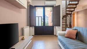 Ein modernes Wohnzimmer mit einer Couch, einem Fernseher, einer Treppe und einer zur Außenseite führenden Tür.