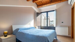 Ein Schlafzimmer mit Bett, Nachttisch, Fenster und Heizkörper.