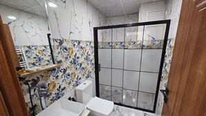 Een badkamer met een douche, toilet, wastafel en een spiegel.