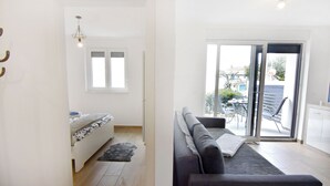 A modern living room with a sofa, a small table, and a window. - Comfort Apartment in Zambratija (Umag)