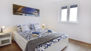 A bedroom with a bed, nightstands, a painting, and a window. - Comfort Apartment in Zambratija (Umag)