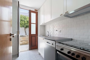 Una cocina moderna con armarios blancos, estufa de acero inoxidable y salpicadero de vidrio.