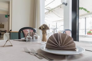 A table set with a folded napkin, a glass jar, and a vase with dried flowers. - Hotel Lido (Gargnano)