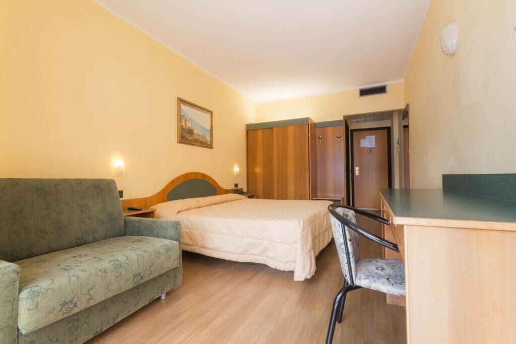 A room with a bed, a sofa, a desk, and a wardrobe.