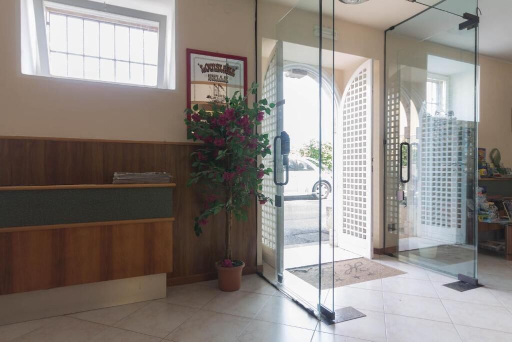 A reception area with a wooden reception desk, a potted plant, and a glass door leading outside.