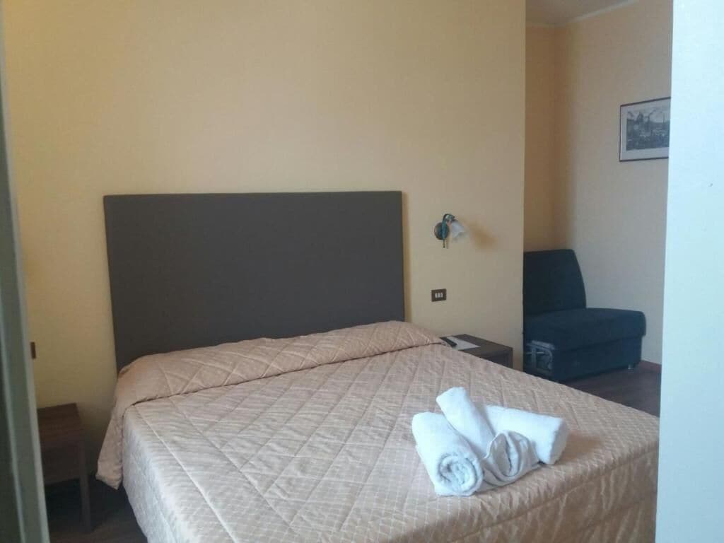 A hotel room with a bed, a chair, and a small table.